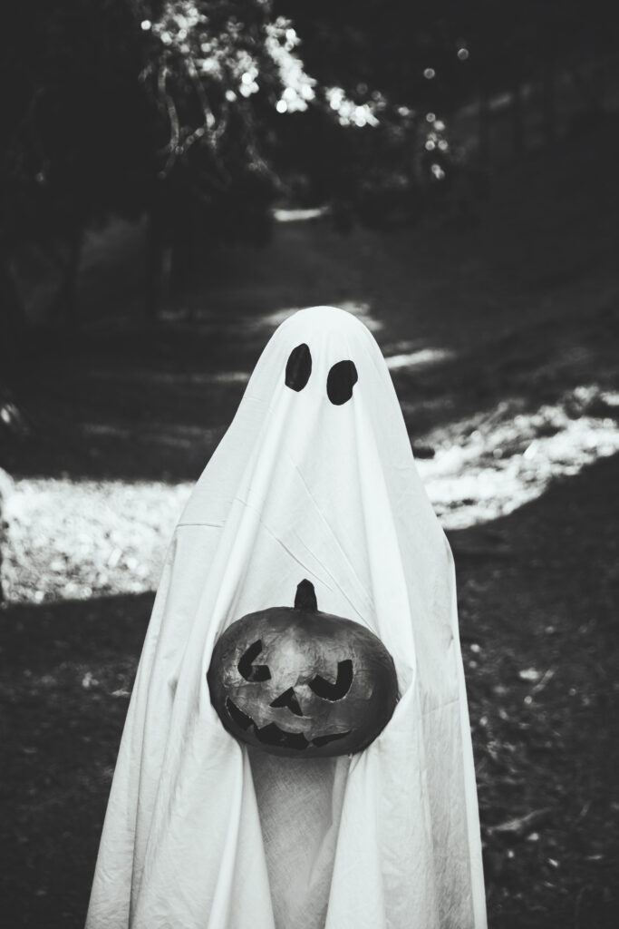 Photo d'une personne déguisée en fantôme tenant une citrouille d'Halloween